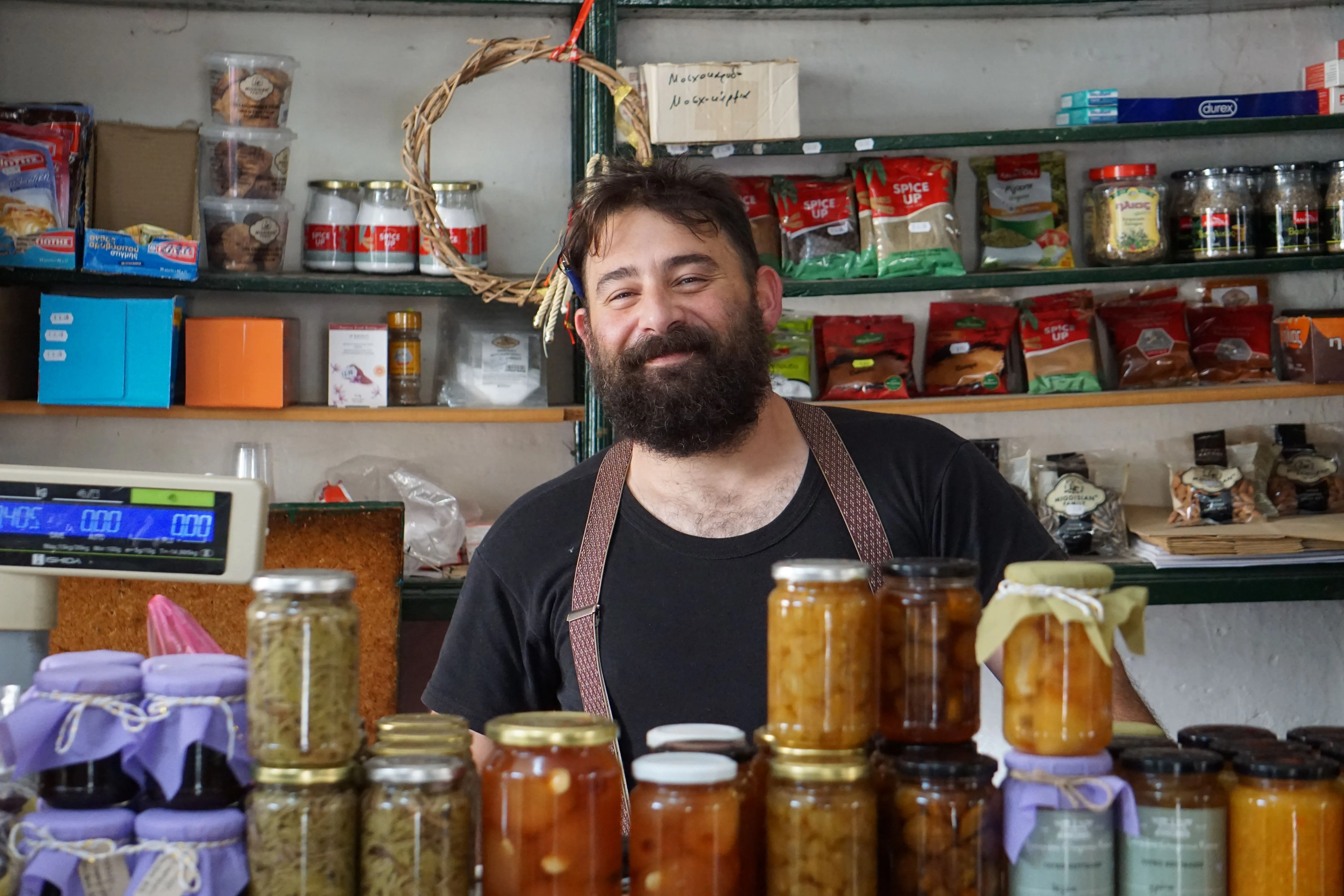 A shop owner smiling behind the counter of his specialty food store